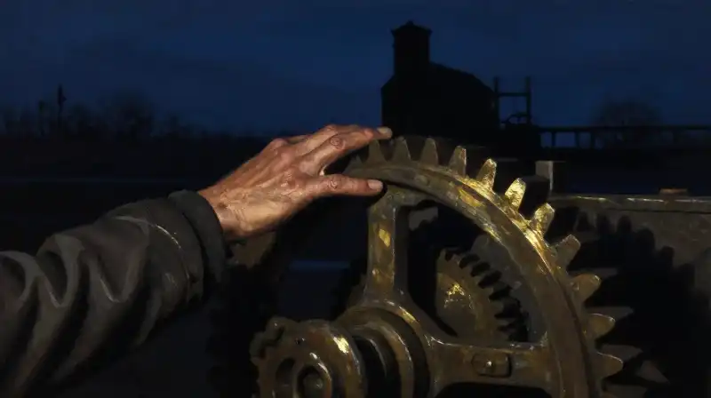 Calloused hands near dark industrial machinery in deep blue tones